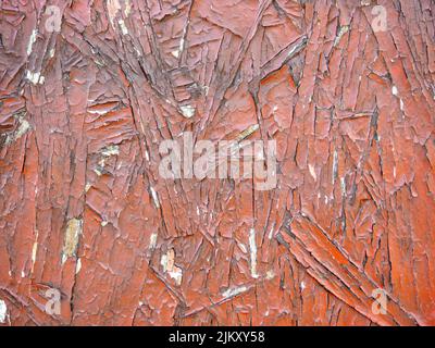 Chipboard in red paint. Background from a painted board. Pattern. Wooden background. Compressed chips. Old shabby wall. peeling paint Stock Photo