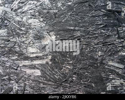 Chipboard in black paint. Background from a painted board. Pattern. Wooden background. Compressed chips. Old shabby wall. peeling paint Stock Photo