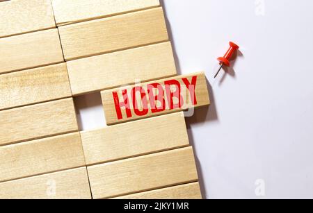 The word HOBBY is made up of wooden cubes lying on an old tree stump against a blurred garden background. Stock Photo