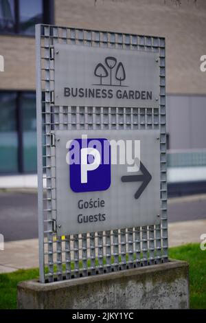 A board with a sign showing the way to the entrance and parking lot of the Business Garden office area Stock Photo