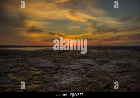 A closeup shot of a cracked and scorched earth against beautiful sunset on the background Stock Photo