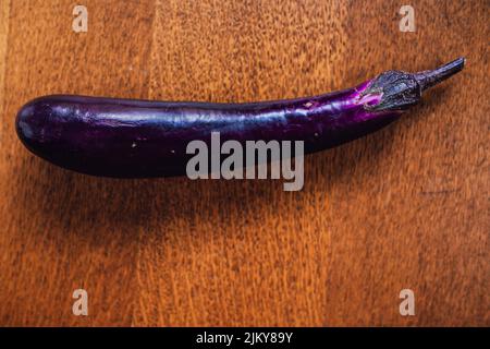 long, skinny purple Chinese eggplant on wooden table Stock Photo