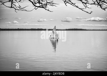 A grayscale shot of a male on a sail in the lake of the Windmill Point Park, Quebec, Canada Stock Photo