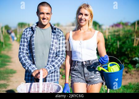Joyful young woman and man at garden holding basket Stock Photo