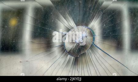 The impact of a stone in the windshield of a car, radial cracks from a dent. Road accident and socio-political unrest (civil commotion or disturbance) Stock Photo