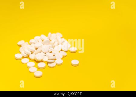 Several white colored pills laid out on top of a blue surface. Medical supplies. Stock Photo