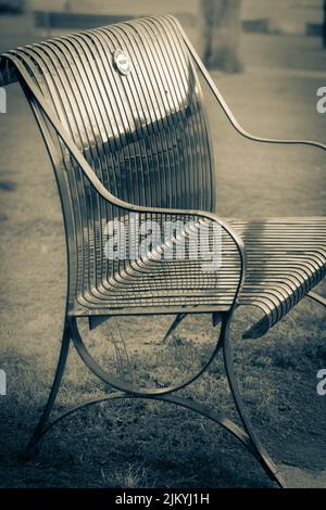 A vertical shot of an empty bench in a park Stock Photo
