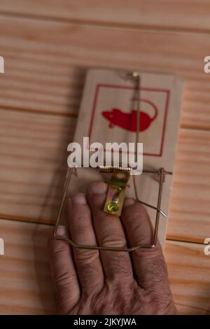 man's hand caught in a wooden mouse trap Stock Photo