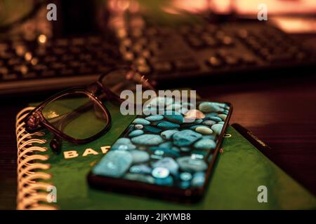 A closeup shot of a Samsung s9 and eyeglasses on a green notebook on a brown table in an office in Nairobi, Kenya Stock Photo