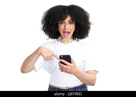Before you leave, have you seen this. Studio shot of an attractive young woman using a smartphone and looking shocked against a white background. Stock Photo