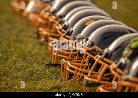 A closeup shot of a row of american football helmets on a field Stock Photo