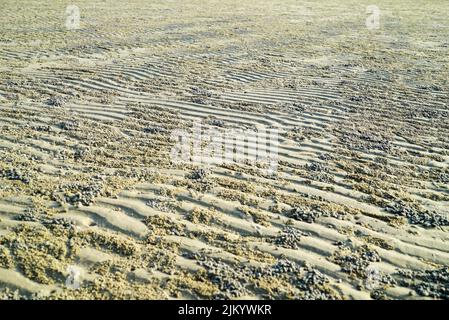 A natural view of wavy sand during low tide on a sunny day Stock Photo