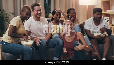 That scene was ridiculously funny. a group of a diverse group of friends relaxing in the lounge at home. Stock Photo