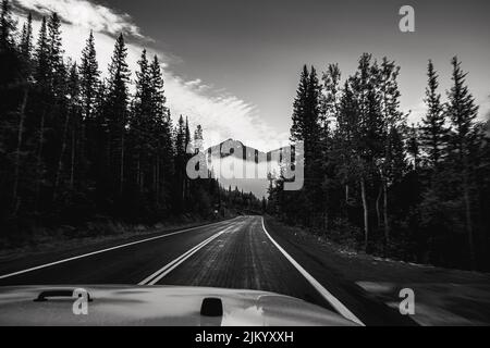 A black and white shot of a beautiful mountainous landscape scene from a car view Stock Photo