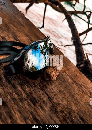A vertical shot of sunglasses with reflections on a wooden surface Stock Photo