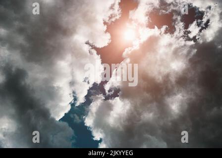 Sun shines through storm clouds, dramatic sky scenery with thunderclouds up above Stock Photo