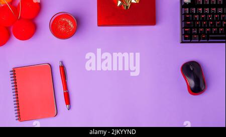 A top view of a notebook, pen, mouse, keyboard, and a candle isolated on a purple background Stock Photo