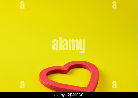A red wooden heart on an intense yellow background with copy space Stock Photo