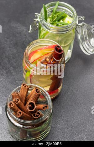 Cinnamon sticks in glass jar. Cinnamon, apple, and lime infused water in glass jar. Black background. Top view Stock Photo