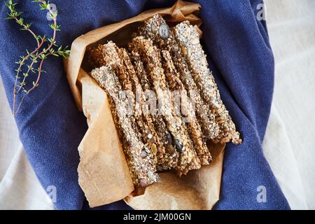 A healthy outside starts from the inside. Overhead shot of seed crackers in a brown paper bag on a blue tablecloth. Stock Photo
