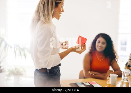 Female entrepreneur presenting her ideas using sticky notes. Young businesswoman brainstorming with her team during a meeting. Creative businesswomen Stock Photo