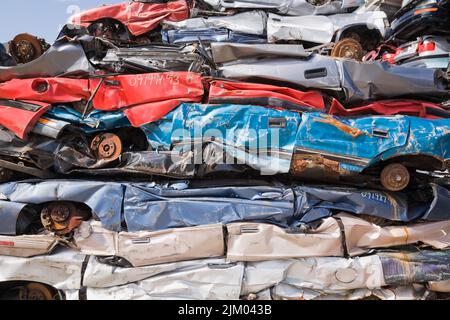 Stacked and crushed discarded automobiles at scrap metal recycling yard. Stock Photo