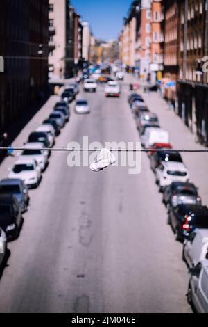 A selective focus of a white shoe hanging on a string in Sodermalm, Stockholm Stock Photo