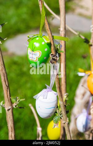 A vertical shot of cute colorful egg decorations hanging from tree branches for Easter celebrations Stock Photo