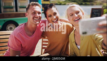 I love taking photos when Im out with friends. a group of friends taking photos outside using a smartphone. Stock Photo