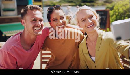 My friends are always there to make me smile. a group of friends taking photos outside using a smartphone. Stock Photo