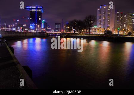 A low angle shot of modern buildings near water at night in Rotterdam, Netherlands Stock Photo