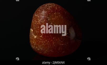 A closeup of a polished Carnelian red agate on a black background Stock Photo