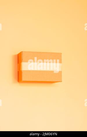 A vertical shot of an orange cardboard packaging mailbox isolated on yellow background Stock Photo