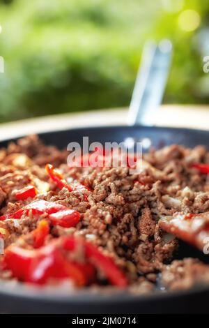 Food stuff. Still life Close up view of hot juicy ground beef stewed with tomato sauce, spices, basil, finely chopped vegetables in a frying pan Stock Photo
