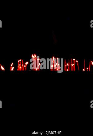 A vertical closeup shot of burning candles in a dark church Stock Photo