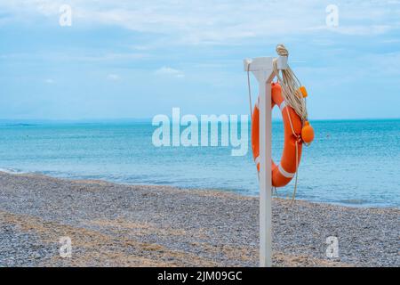 Life ring beach sea buoy orange closeup saving rescue round, concept red guard from emergency from ocean assistance, shore safe. Survival background Stock Photo