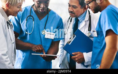 Group of doctors, medical professionals and workers doing reaching on a tablet, browsing on the internet and discussing a health case together at a Stock Photo
