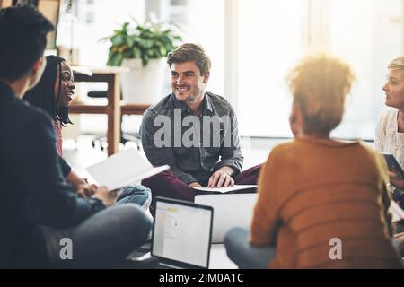 Creative business team in a meeting planning and brainstorming together while sitting on the floor. A group of colleagues or coworkers talking and Stock Photo