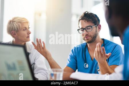 Group of medical doctors planning, brainstorming and discussing patients records in a meeting. Healthcare professional team leader briefing colleagues Stock Photo