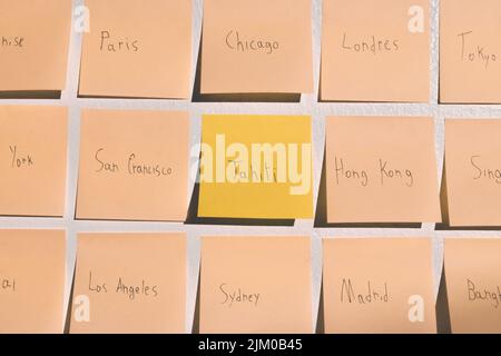 A closeup shot of a wall with post notes of different city names Stock Photo