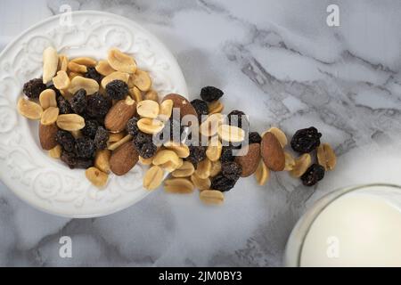 A top view of a trail mix in a white plate on a marble table Stock Photo