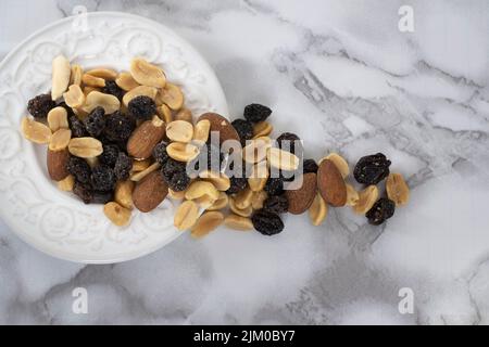 A Top view of a trail mix in a white plate on a marble table Stock Photo