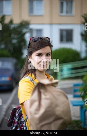 A girl holds out a paper bag with a purchase on the street. Delivery concept. Vertical photo. Stock Photo