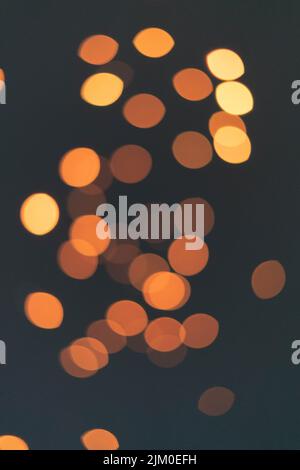 A scenic shot of blurry orange bokeh lights illuminated in the dark Stock Photo