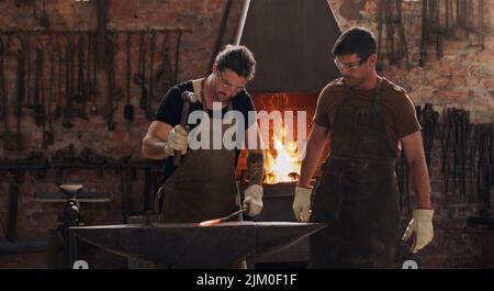 We use metal to create just about anything. two metal workers working together in a workshop. Stock Photo