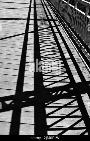 A vertical grayscale shot of the shadows of railings on a bridge Stock Photo