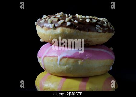 closeup various colorful donuts in a column on a dark background Stock Photo