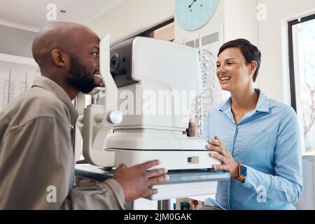 Optometrists are eternal optimists. an optometrist examining her patients eyes with an autorefractor. Stock Photo