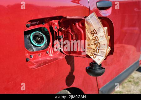 An open fuel tank of a car with a bundle of fifty euro banknotes in the lid, symbol of the rising fuel price and increasing transportation costs. Stock Photo