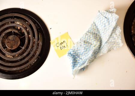 A top view shot of a dirty stove with a yellow sticky note saying clean me Stock Photo